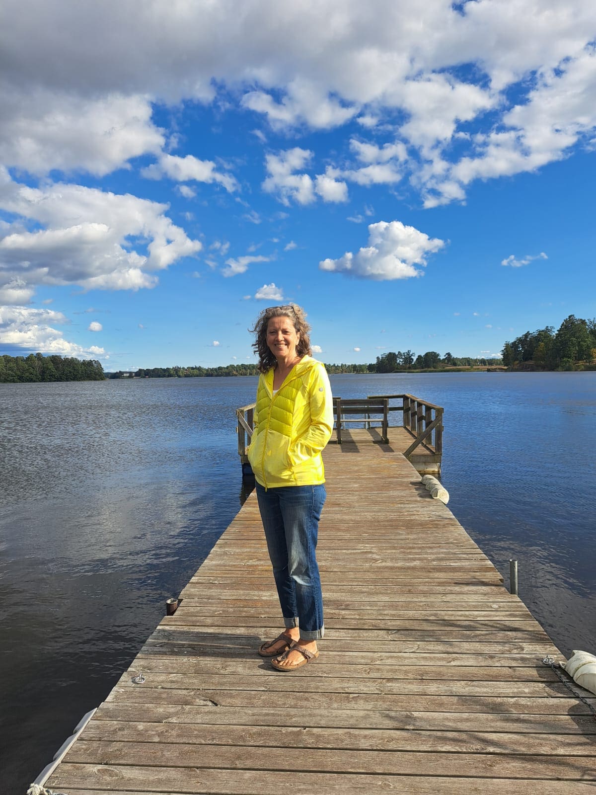 Karin Intveen steht lächelnd auf einem Holzsteg an einem See